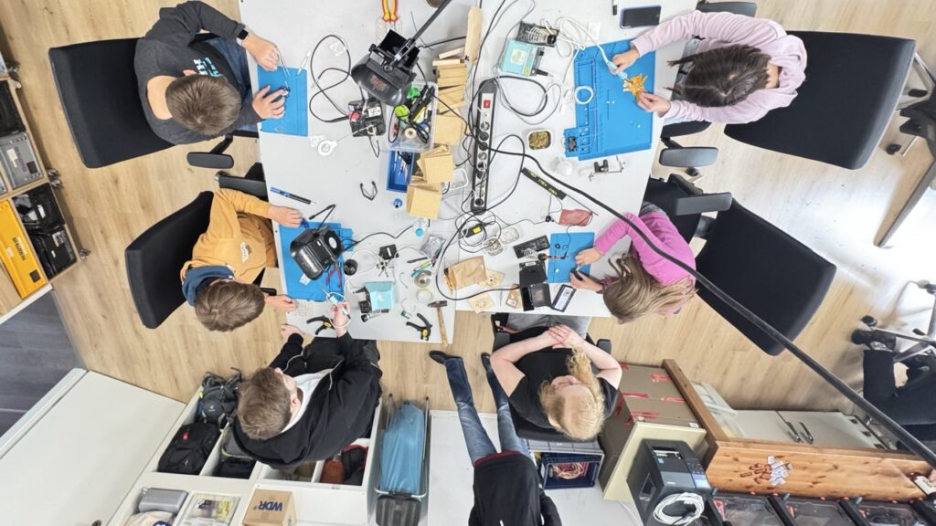 Blick aus der Vogelperspektive auf eine Gruppe Kinder, die löten