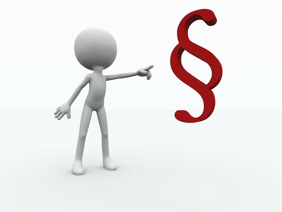 Puppe zeigt auf Paragraphenzeichen